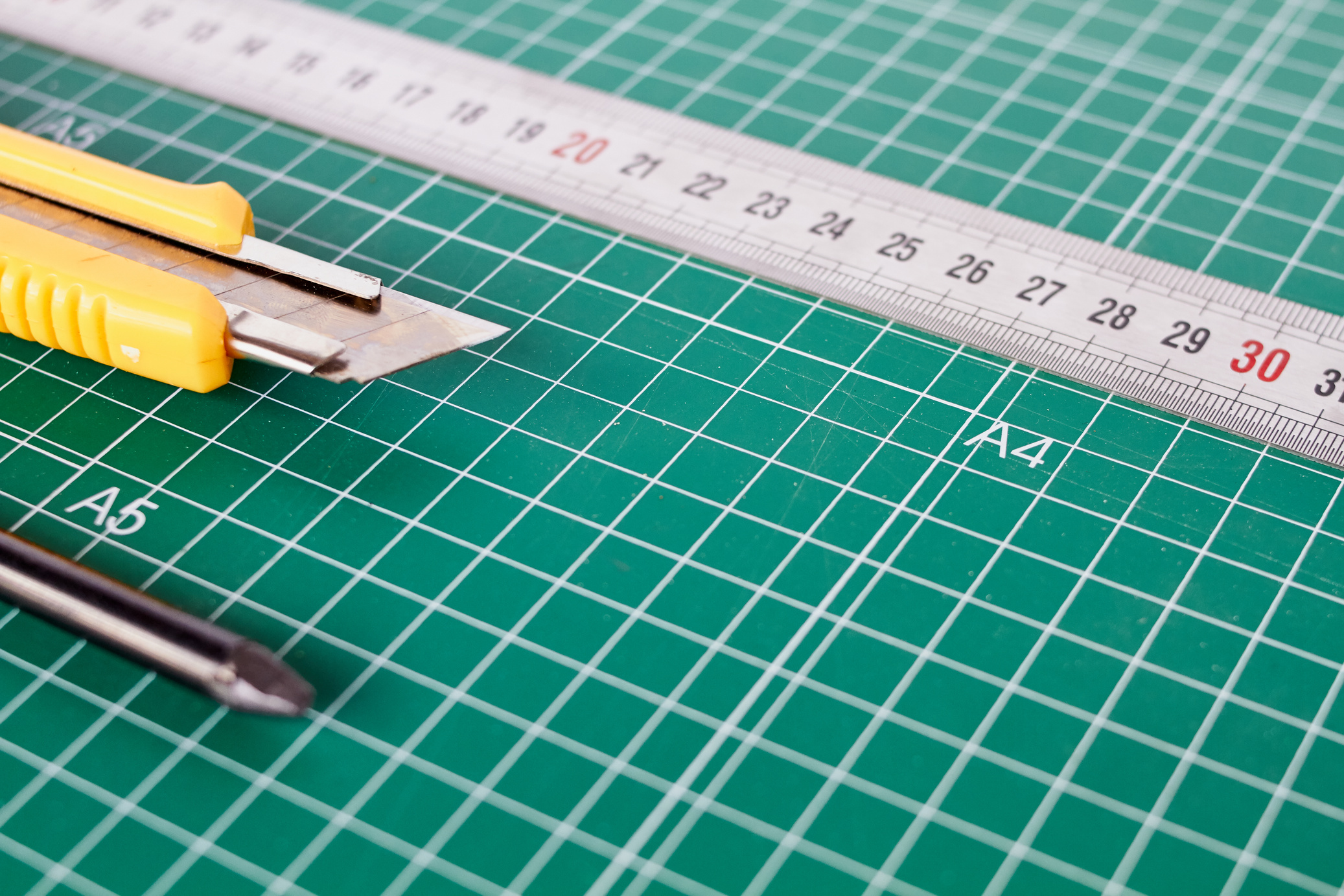 Cutter, Ruller and Pencil on a Green Cutting Mat