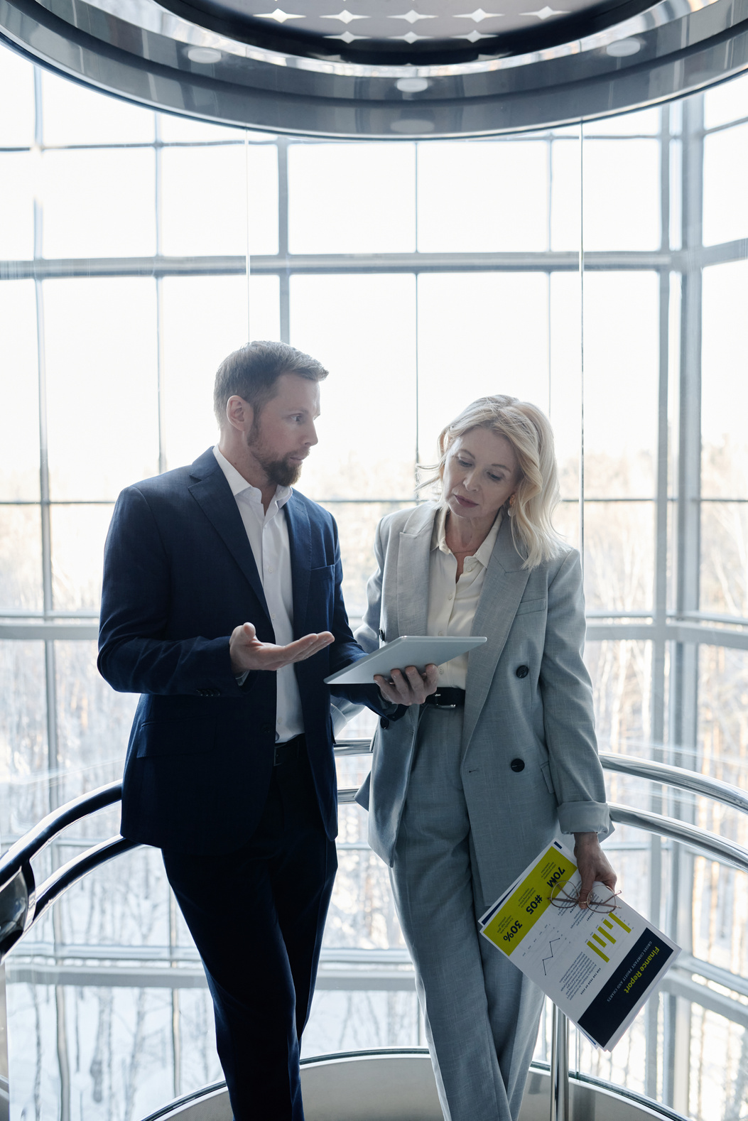 Man in Suit Holding a Tablet Communicating with a Woman Holding Documents
